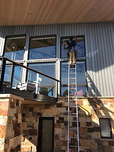 man on ladder washing windows
